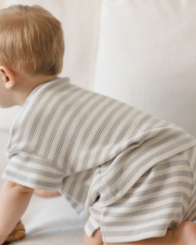 Child wearing a striped outfit sitting on a light-colored surface