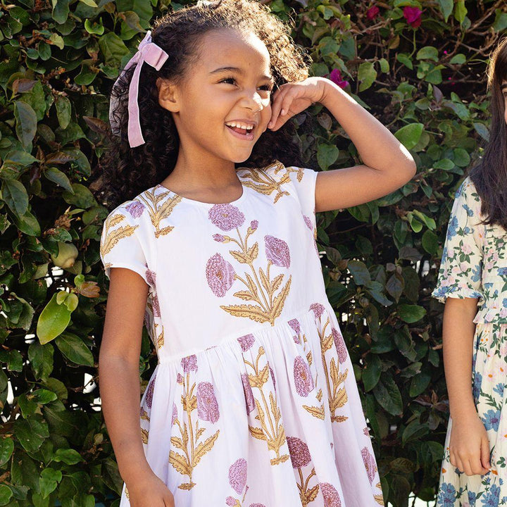 young girl modeling the dress, standing in the sunligh wearing the dress with lavender  marisols on it 