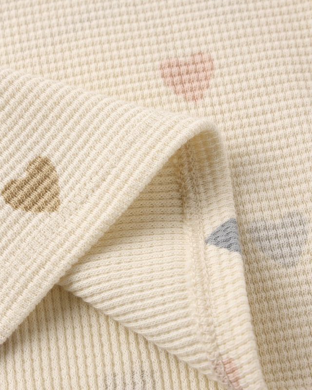 Close-up of textured fabric with hearts on a beige background