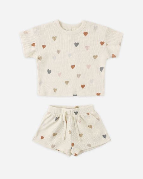 Children's outfit with a t-shirt and shorts featuring heart patterns on a white background