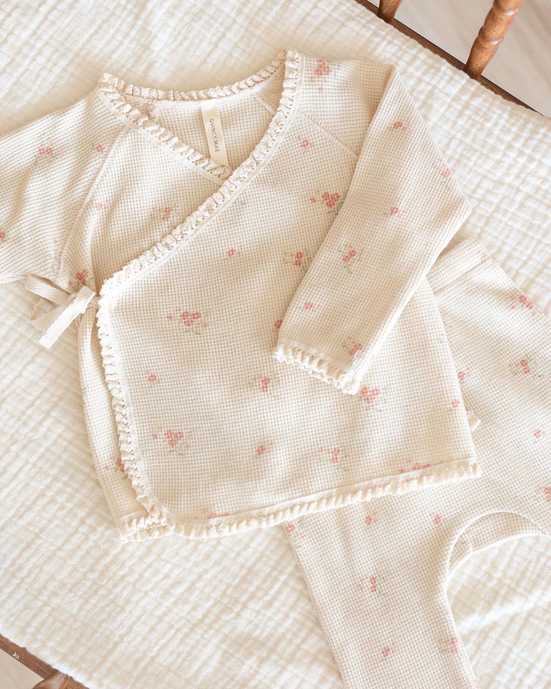 close up of take home set, beige color with tiny pink rosebuds all over it. top wraps and ties at the center of the top. 