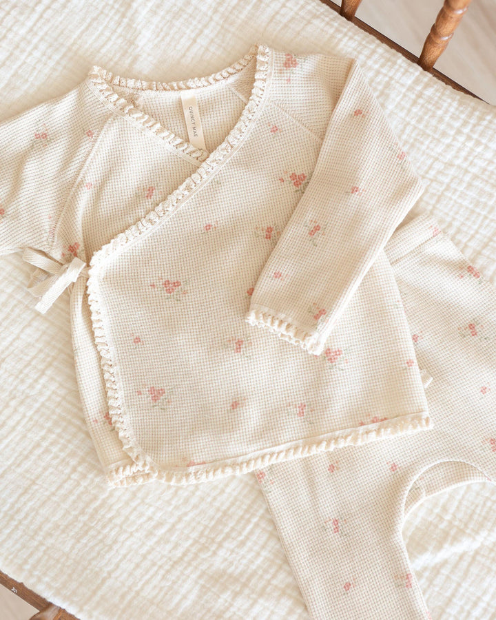 close up of take home set, beige color with tiny pink rosebuds all over it. top wraps and ties at the center of the top. 