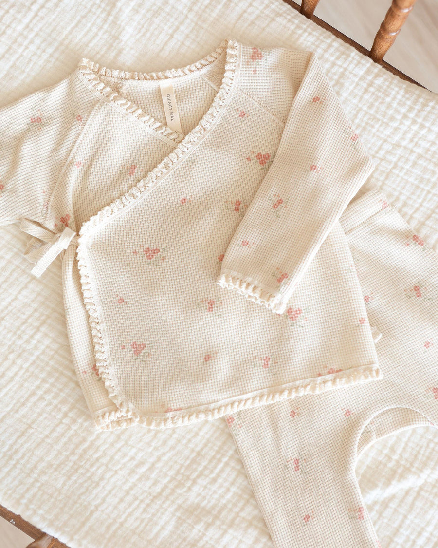 close up of take home set, beige color with tiny pink rosebuds all over it. top wraps and ties at the center of the top. 