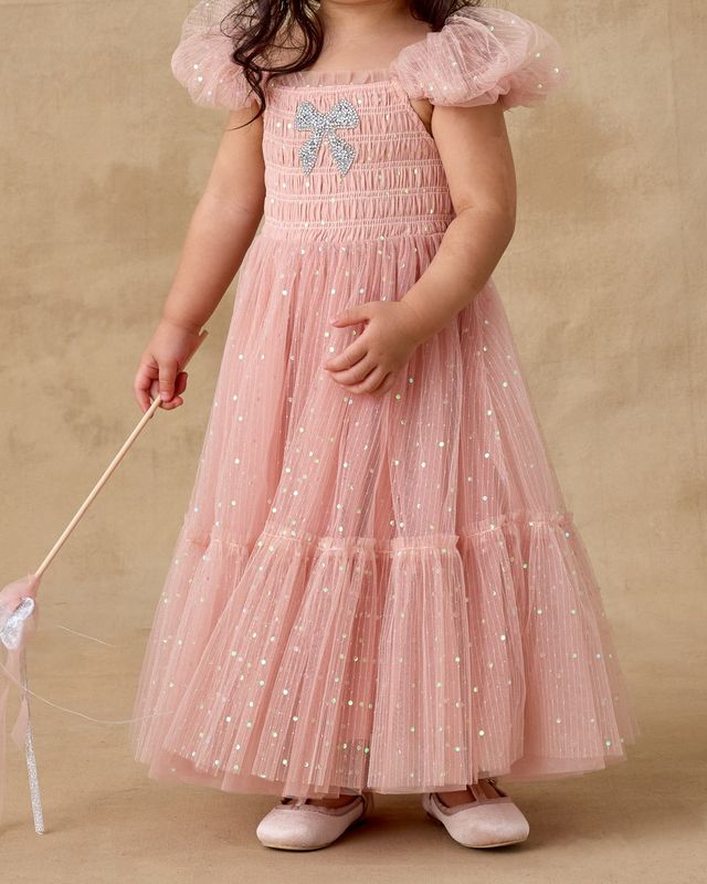 Child wearing a pink dress with star patterns on a beige background
