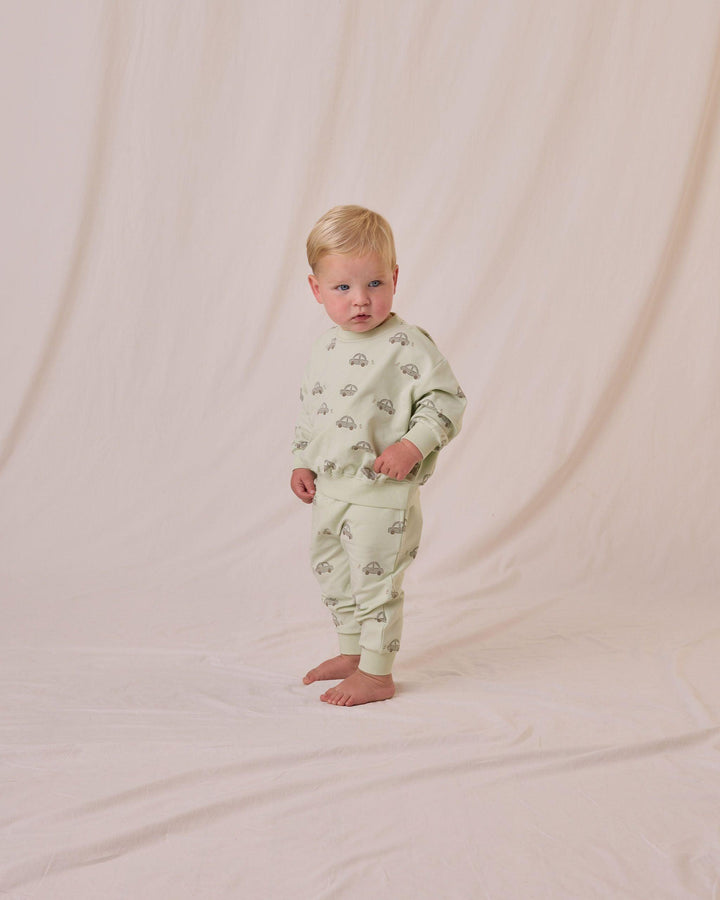 toddler boy modeling the car sweatsuit standing looking comfortable. the top hits below the waist and the sweatpants have a nice relaxed fit