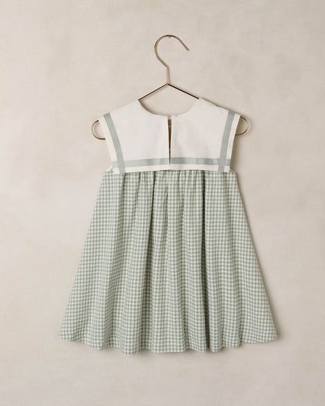 Green checkered dress on a hanger against a beige background