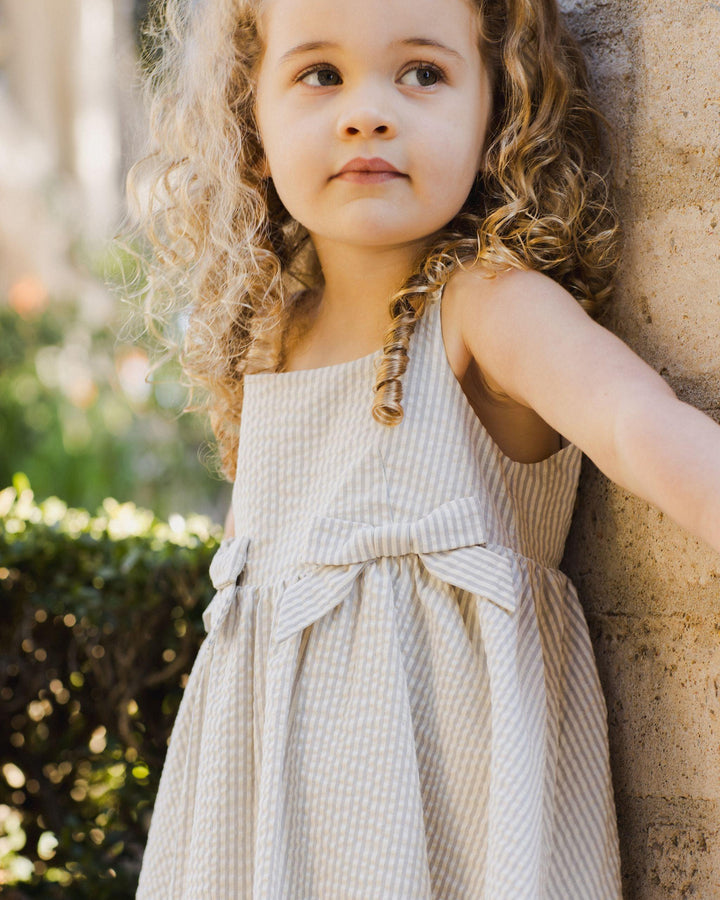 little girl wearing the sage stripe dress, close up of the bows and textured fabric 