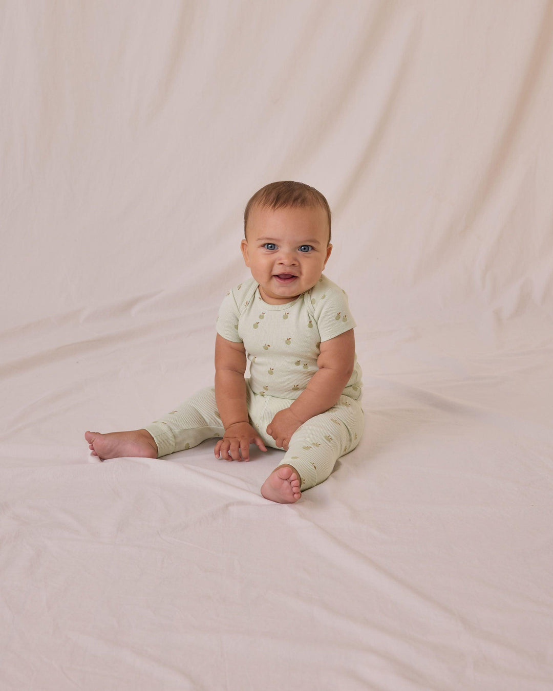 baby sitting in the ribbed mint set with tiny apples all over it. 