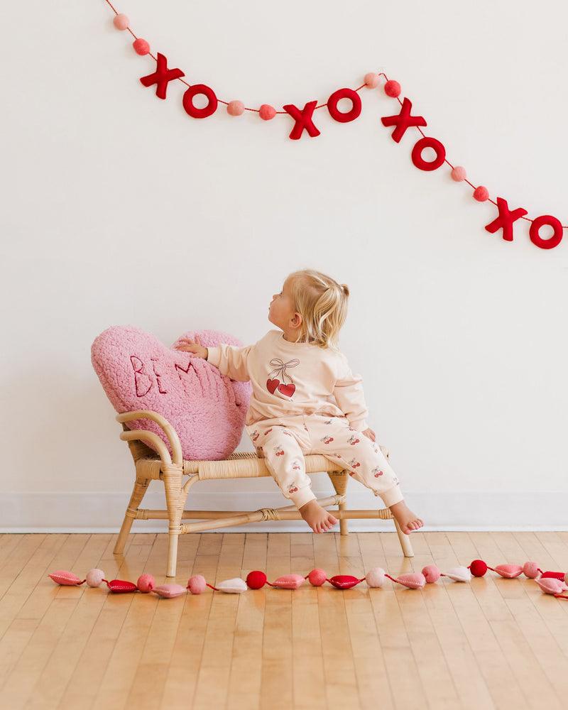 little girl modeling the cherries sweatsuit with Valentines Day decorations as a back drop