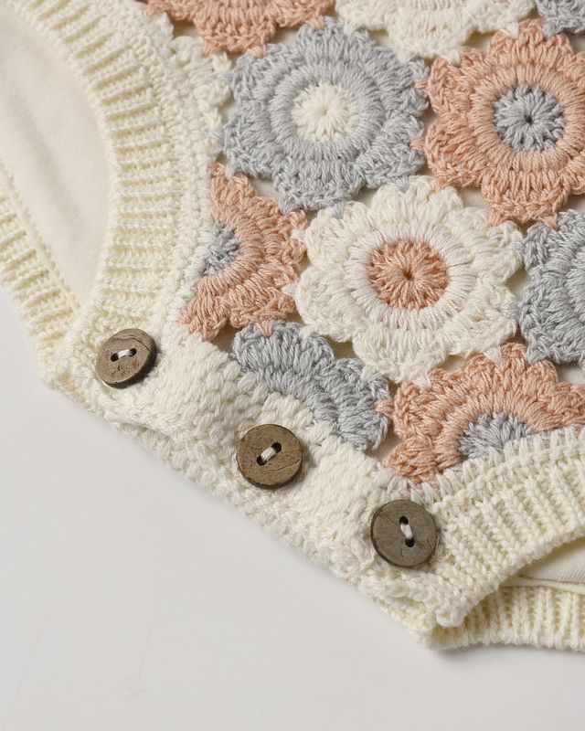 Close-up of a crocheted fabric with floral patterns and buttons on a white background