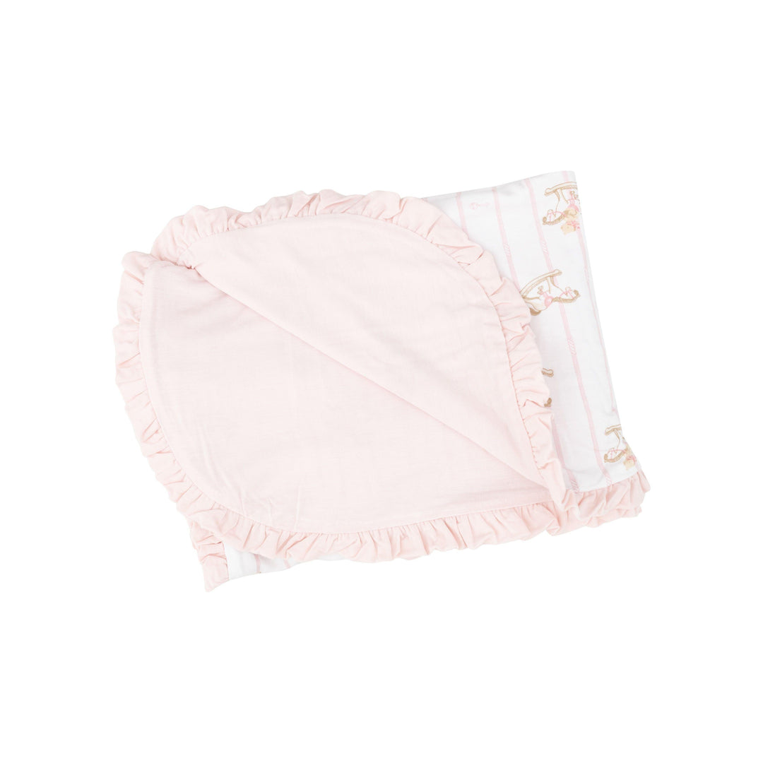 receiving blanket with pastel pink on one side and white with rocking horses on the other. ruffles on the edge of the blanket 