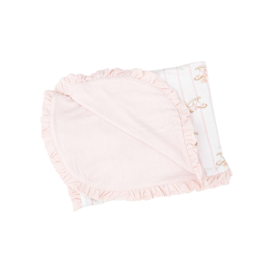 receiving blanket with pastel pink on one side and white with rocking horses on the other. ruffles on the edge of the blanket 