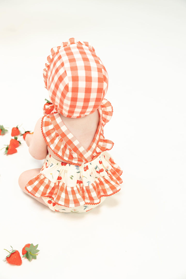 baby modeling the ruffle sunsuit and sitting facing forward. from this angle you can see the back of the sunsuit and all of the details and ruffles. 