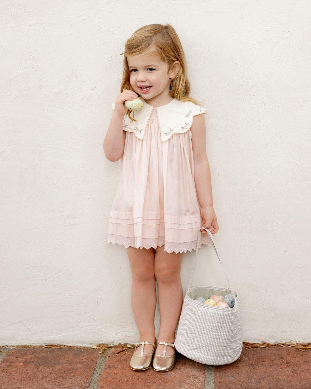 little girl modeling the pink dress with big dramatic collar and embroidery along the collar and lace trim at the hem. 