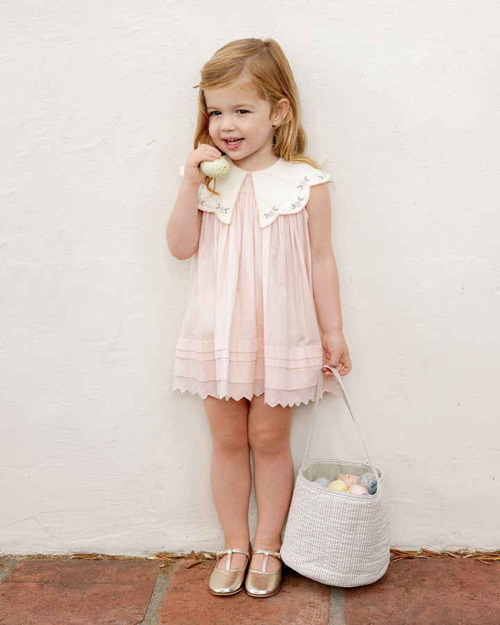 little girl modeling the pink dress with big dramatic collar and embroidery along the collar and lace trim at the hem. 