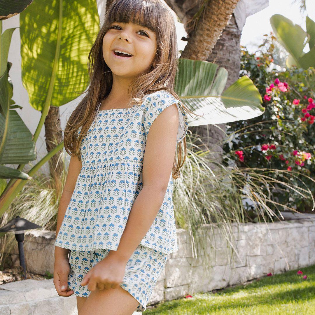 little girl modeling the short set. white with tiny blue flowers and green stem. cap sleeve with peplum bottom. 