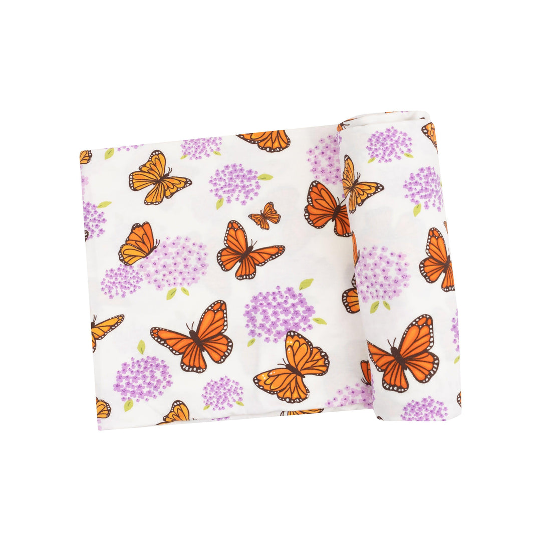baby swaddle with orange monarch butterflies and purple milkweed flowers on it. 