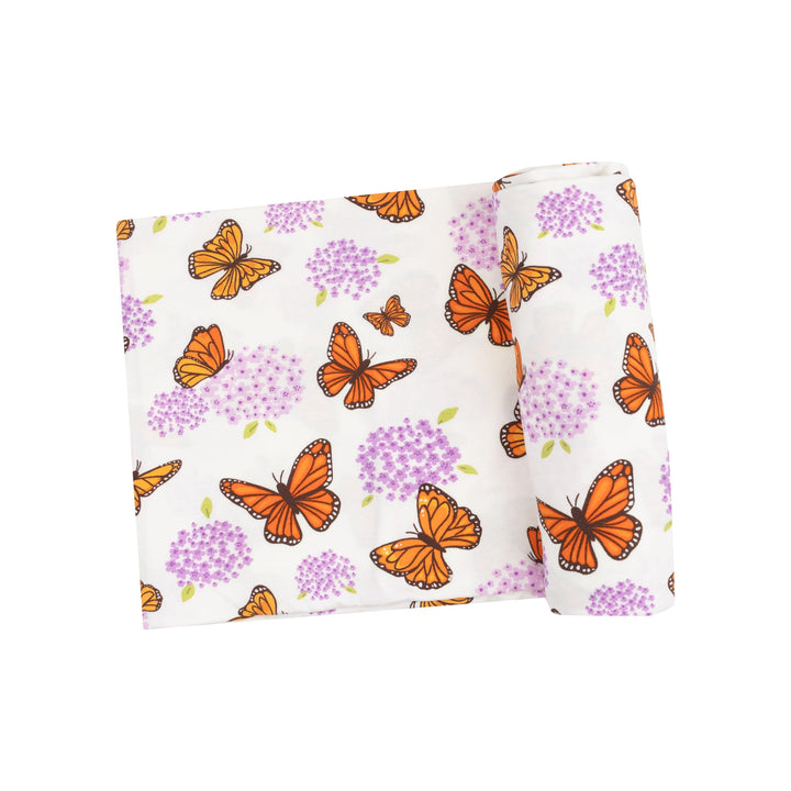 baby swaddle with orange monarch butterflies and purple milkweed flowers on it. 