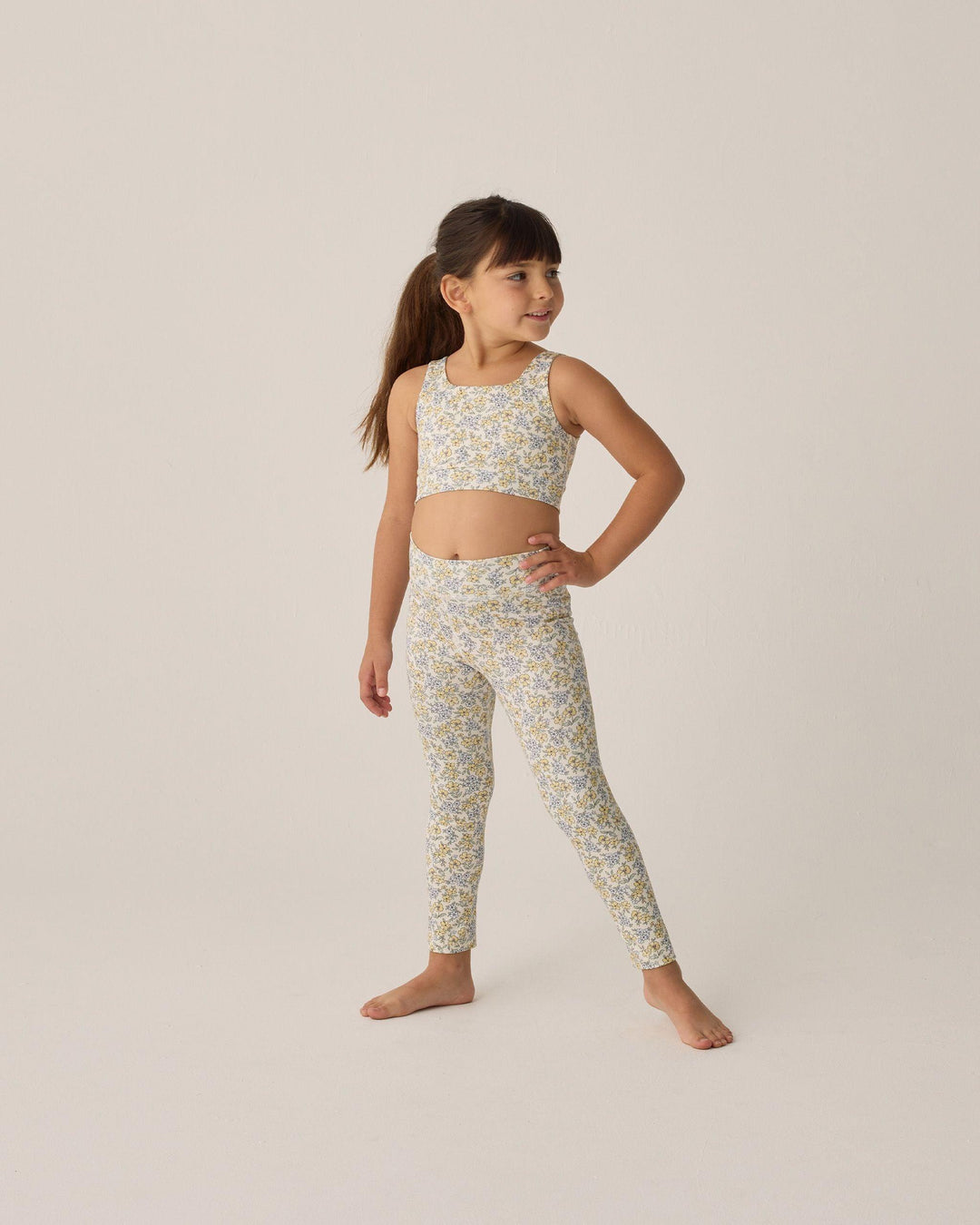 young girl modeling a pair of leggings with yellow and blue flowers all over them