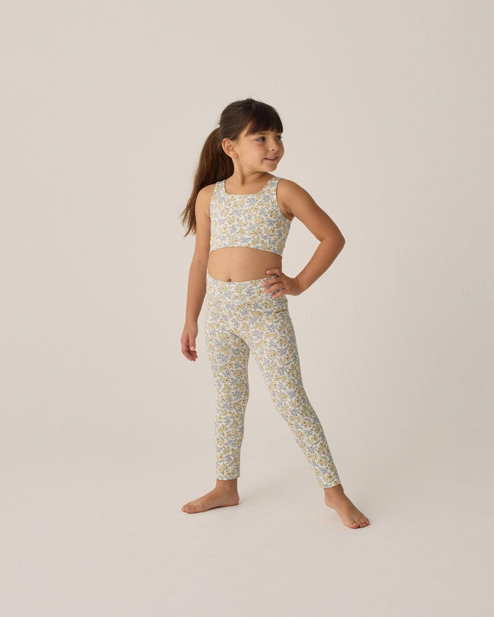 young girl modeling a pair of leggings with yellow and blue flowers all over them