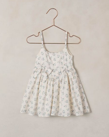 Floral dress on a hanger against a plain background