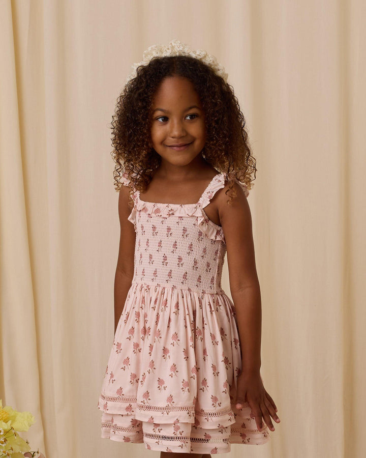 little girl modeling the birdie dress. the color pink really pops and here and shows how subtle the pink is and how delicate the rosebud pattern
