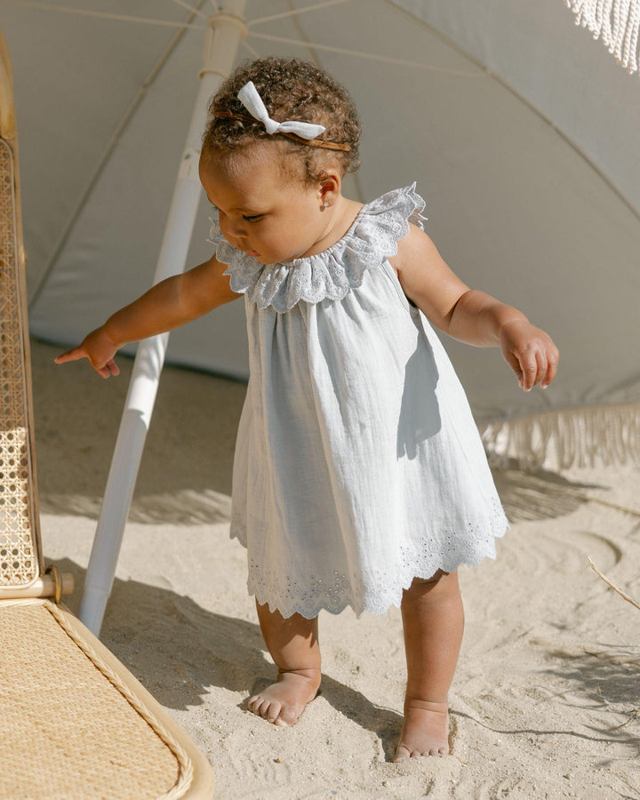 baby modeling the isla dree in sky blue. big eyelet collar at the top of the dress and eyelet all along the bottom. 