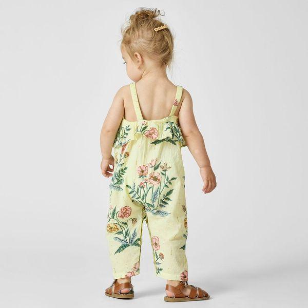 baby girl modeling the pale yellow jumpsuit with flowers on it. the jumpsuit hits at the ankles and has a relaxed fit. 