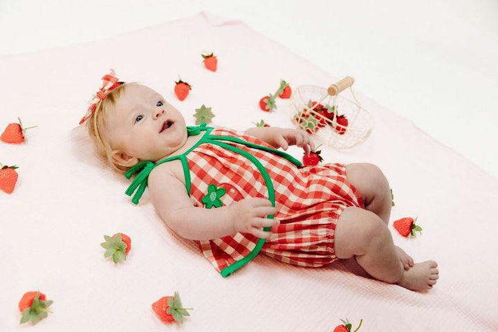 baby laying on the floor in the red gingham sunsuit. plenty of room to roll around and play