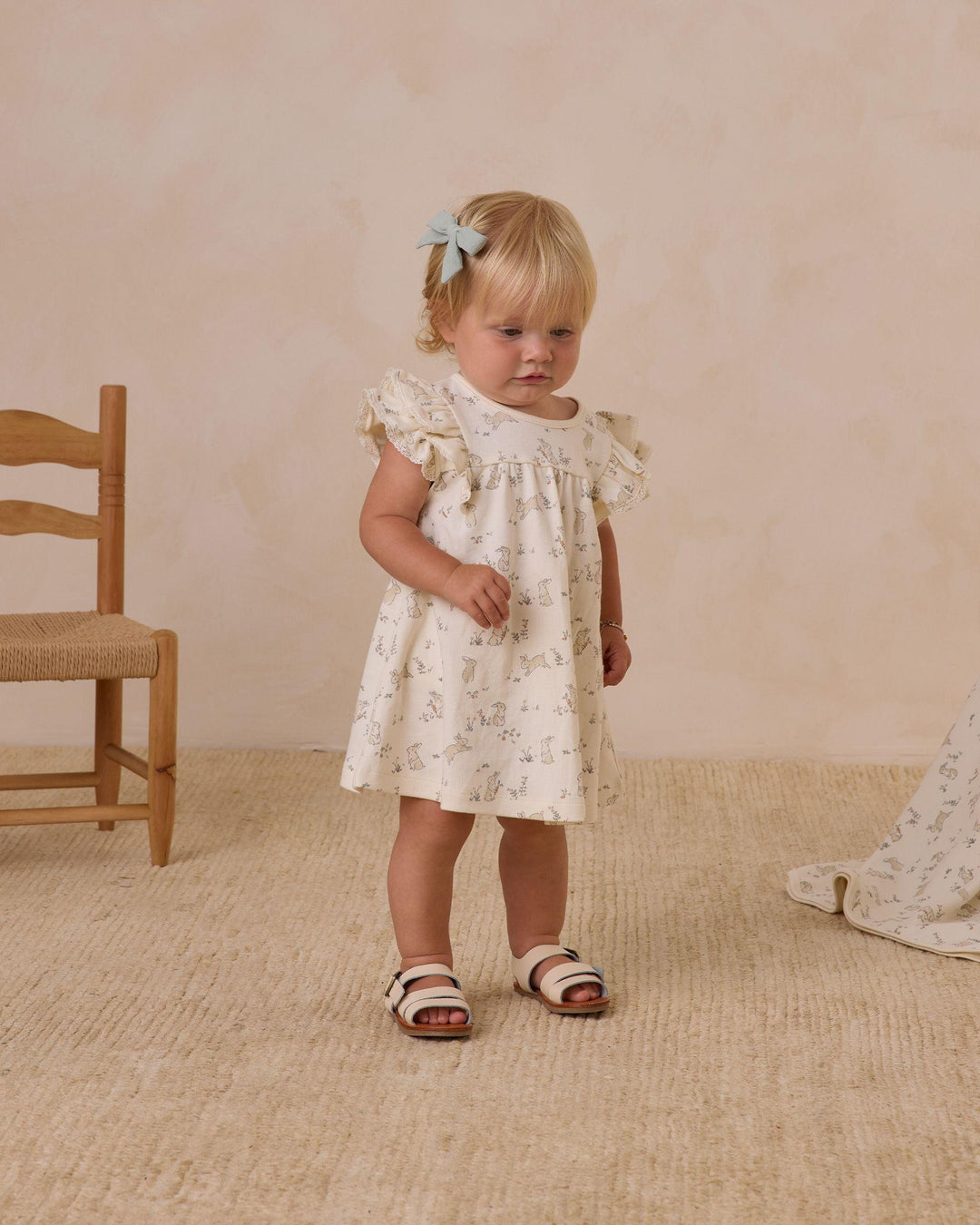 baby girl wearing the bunnies flutter sleeve dress. it hits at the knee and provides a short sleeve with ruffles. 