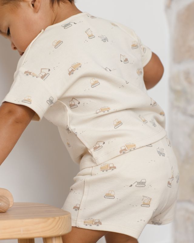 Child wearing a cream-colored outfit with printed patterns on a white background