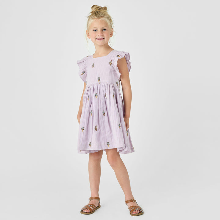 little girl modeling the lavender soft serve dress. this shows the ruffle being dramatic and having more of a sleeve/coverage. also hits knee length. 