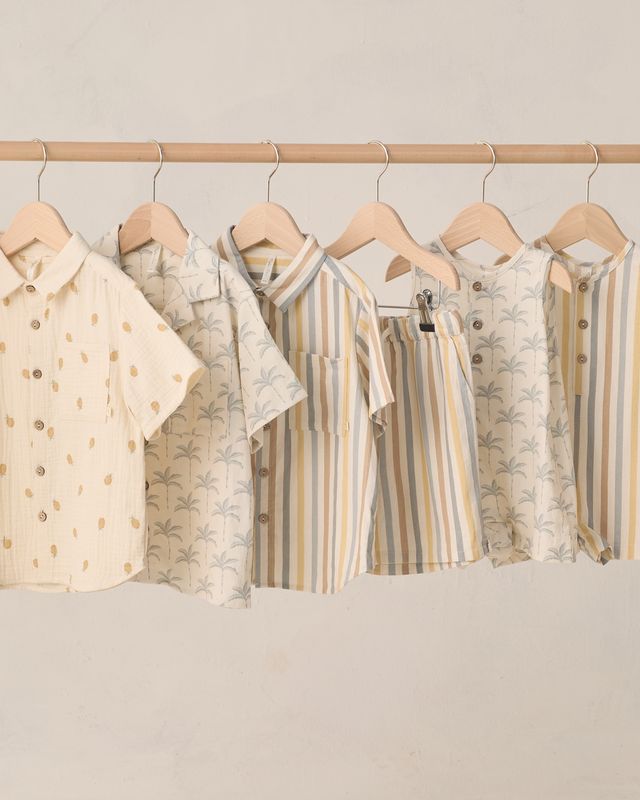 Row of children's shirts on hangers against a neutral background