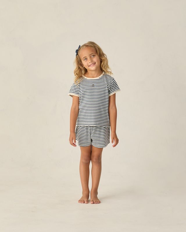 Young girl wearing a striped outfit on a plain background