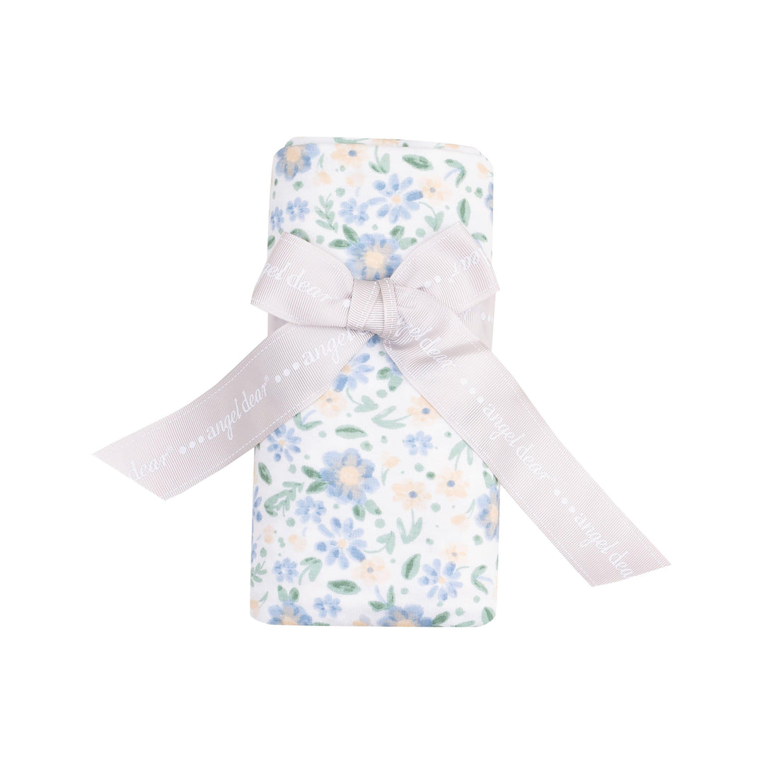 baby swaddle with delicate blue and peach floral print rolled and tied with a ribbon. this is how the swaddle is packaged and sold from the vendor. 