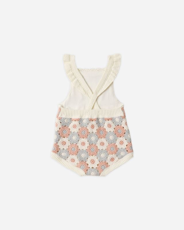 Baby romper with floral patterned bottom and white top on a white background