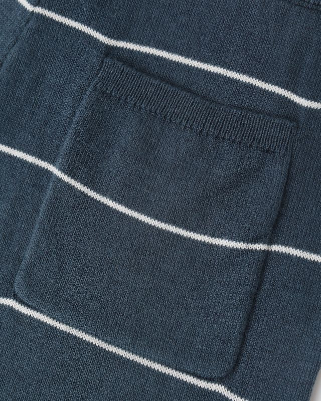 Close-up of a blue sweater with white stripes and a pocket.