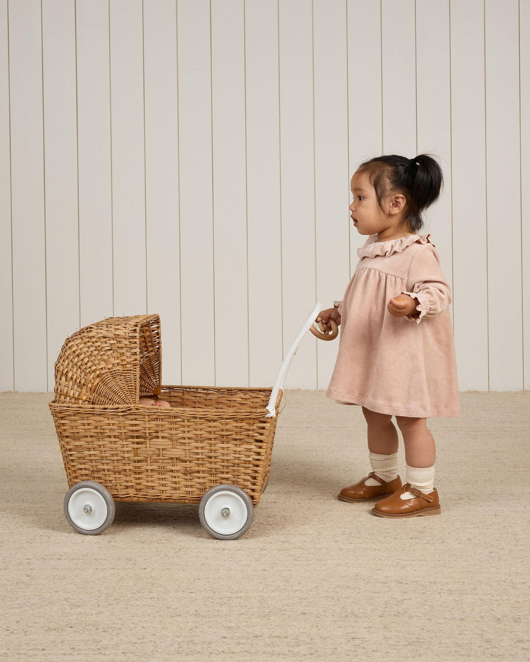 baby modeling the blush velour baby dress while pushing a baby stroller toy