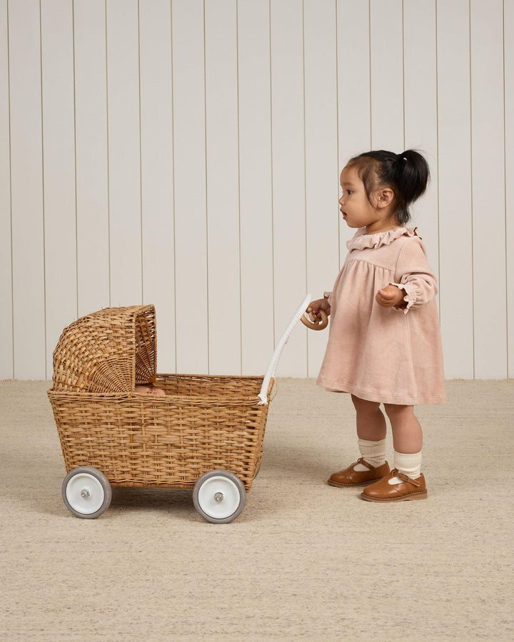 baby modeling the blush velour baby dress while pushing a baby stroller toy