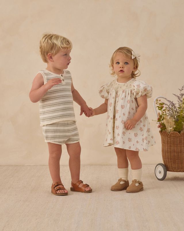 Two children holding hands in a studio setting with a neutral background