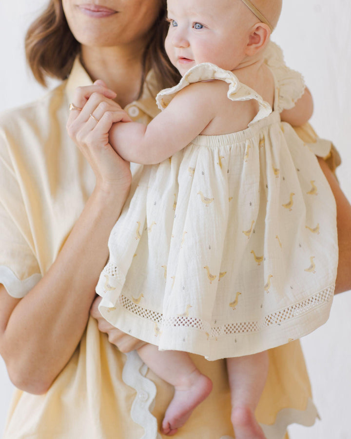 this picture shows a baby being held by its mom. Shows the back of the dress and how the ruffles sit on the back of baby. 