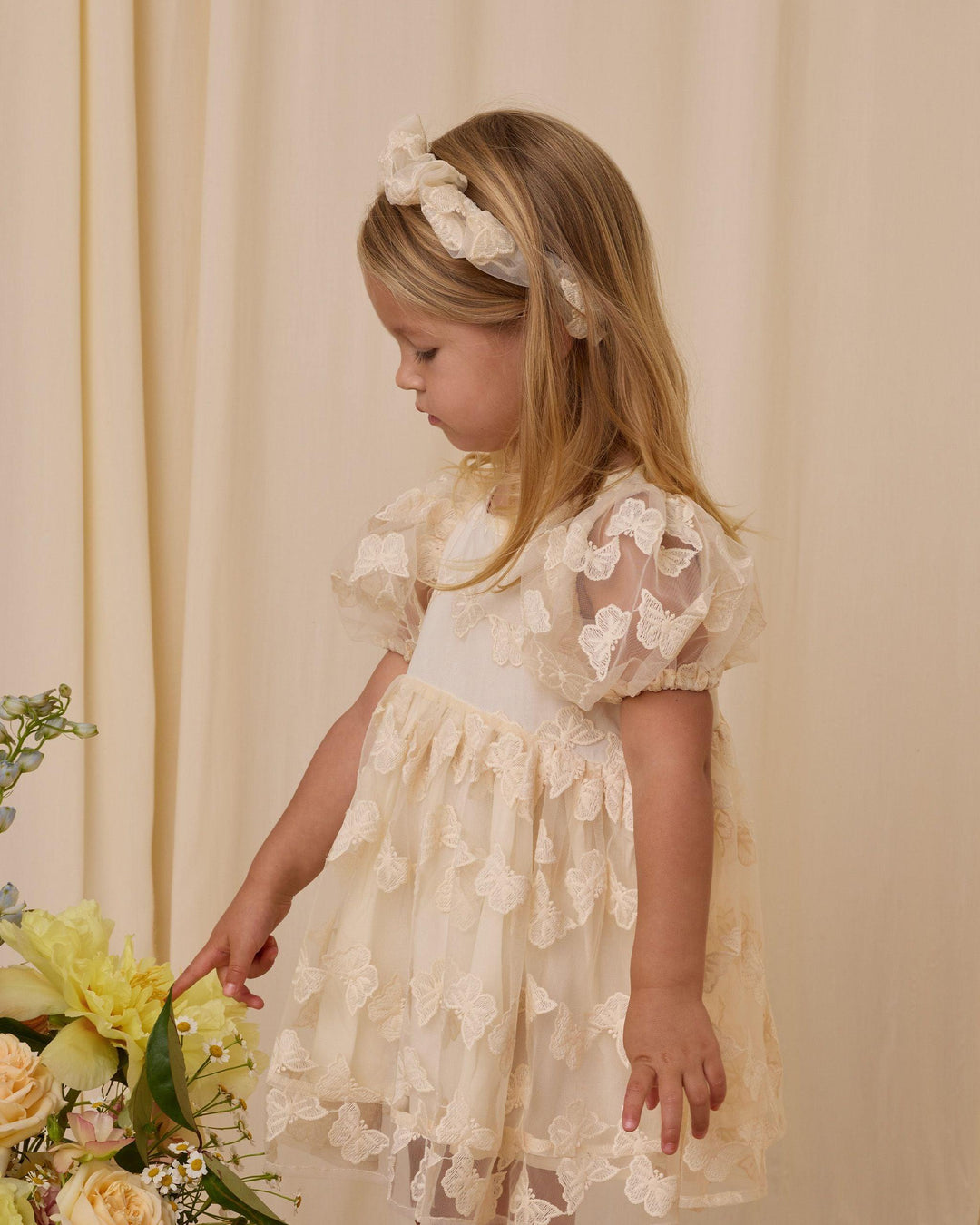 little girl modeling the ivory luna dress with sheer butterfly overlay