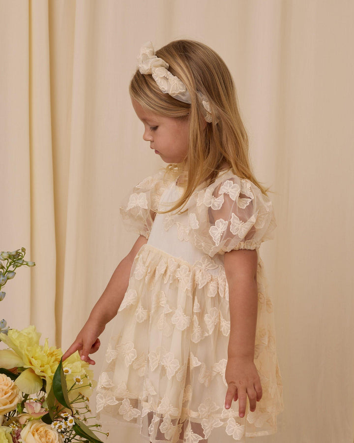 little girl modeling the ivory luna dress with sheer butterfly overlay
