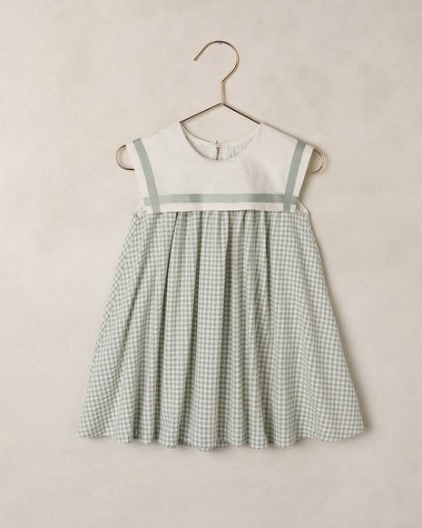 Green checkered dress on a hanger against a beige wall