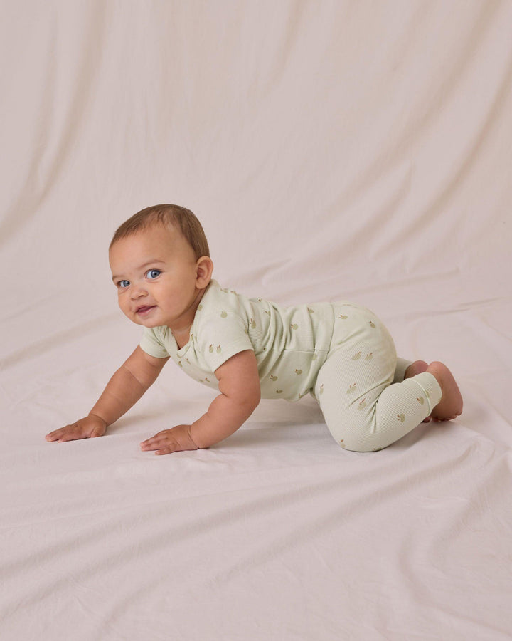 baby modeling the ribbed set and crawling along the floor 
