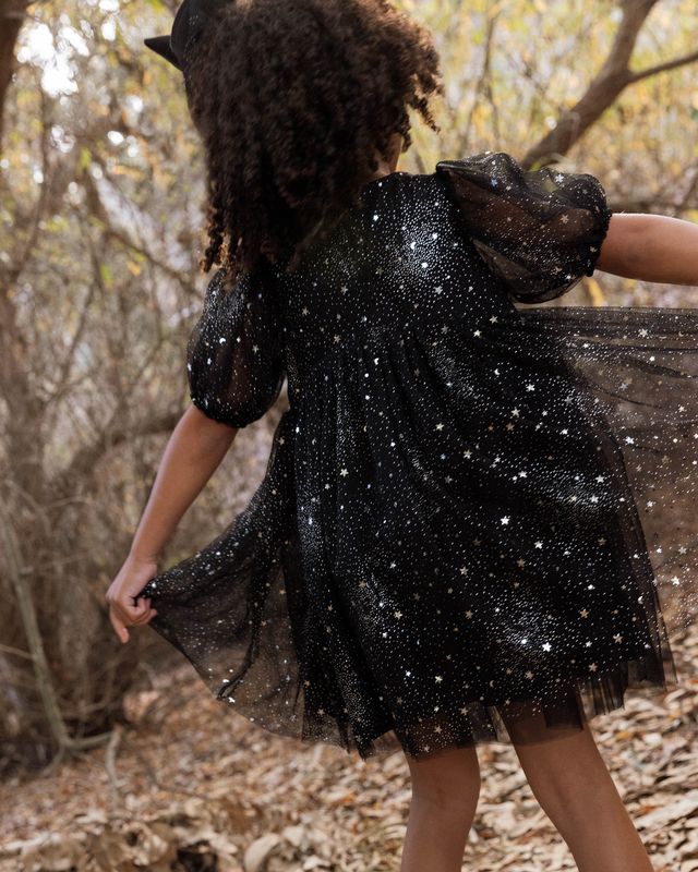 Person wearing a black sequin dress in a forest setting
