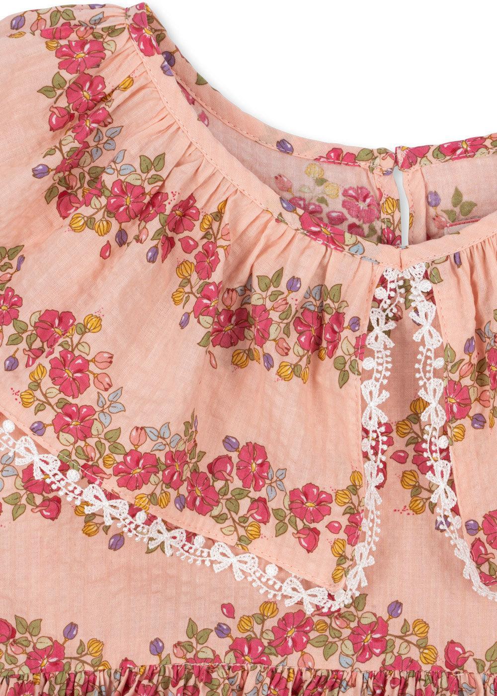 up close view of the pink floral print and the trim which is a white bow that looks like delicate lace. 