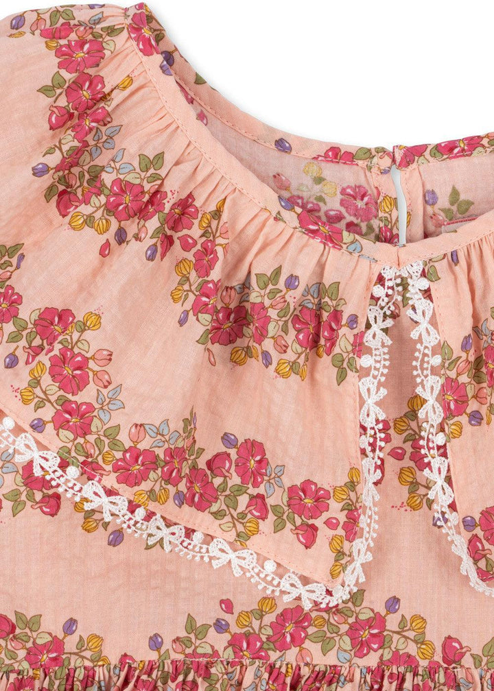 up close view of the pink floral print and the trim which is a white bow that looks like delicate lace. 