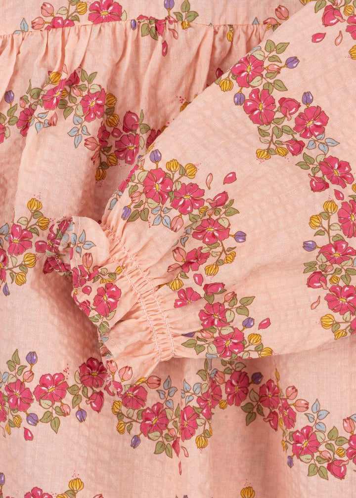 close up look of the pink romper with pretty florals all over and a delicate ruffle at the sleeve. 