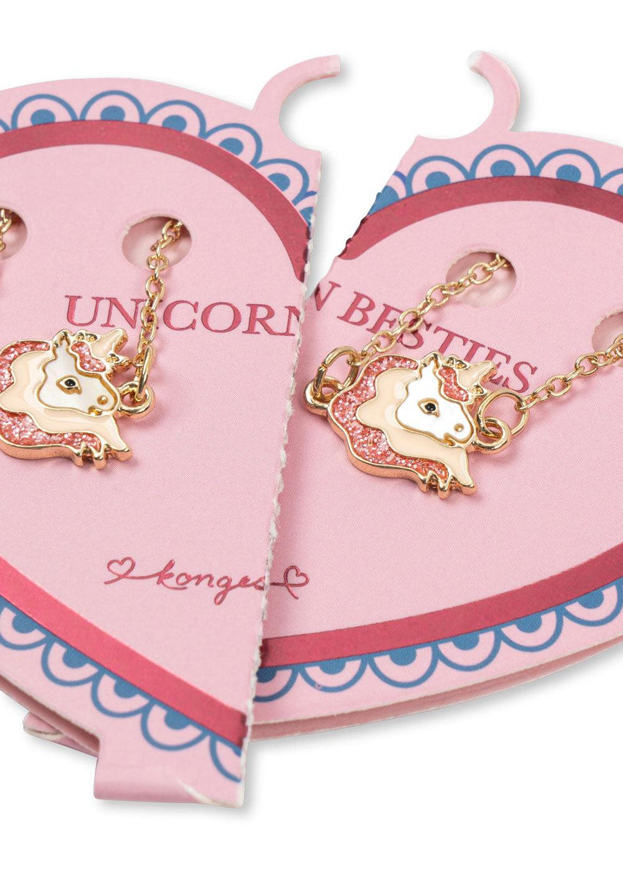 picture of two unidorn pendants attached to a gold link chain on a pink cardboard heart. 